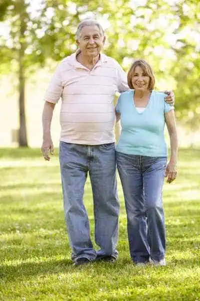 Adultos mayores sonriendo caminando por una zona verde -. Pañales para adultos