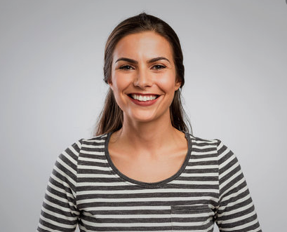 Mujer castaña sonriendo con camisa de rayas.