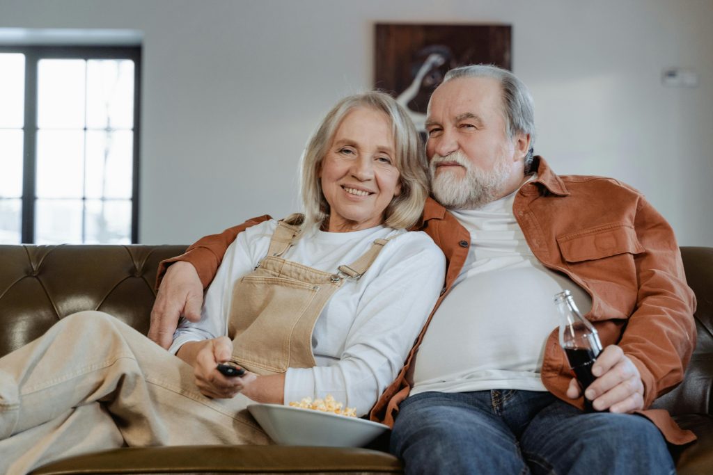 Adultos mayores sentados en el sofá viendo la TV.