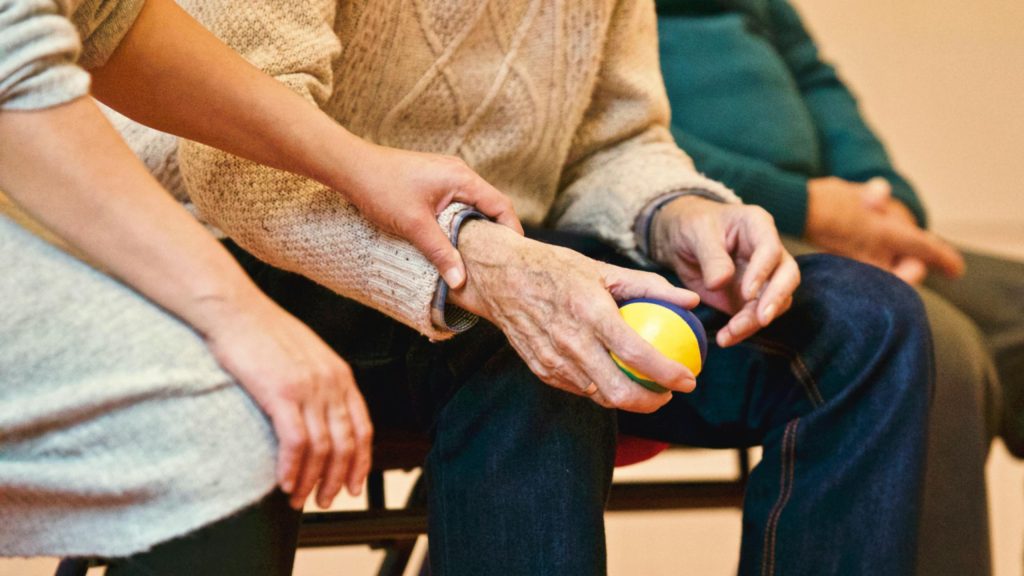 Cuidadora agarra la mano de un adulto 
mayor. calzón desechable para adulto