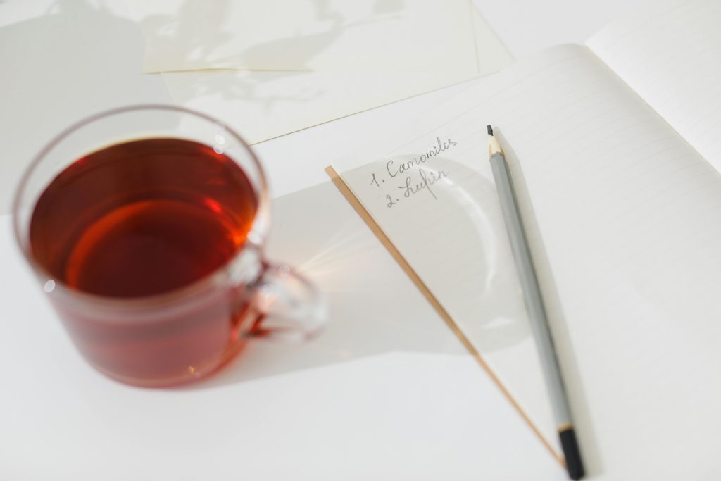 Taza con té y pluma encima de una hoja de papel. Pañales para adultos